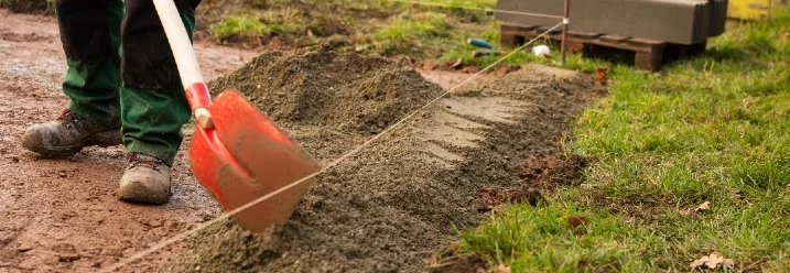 Person verteilt Kies mit Schaufel
